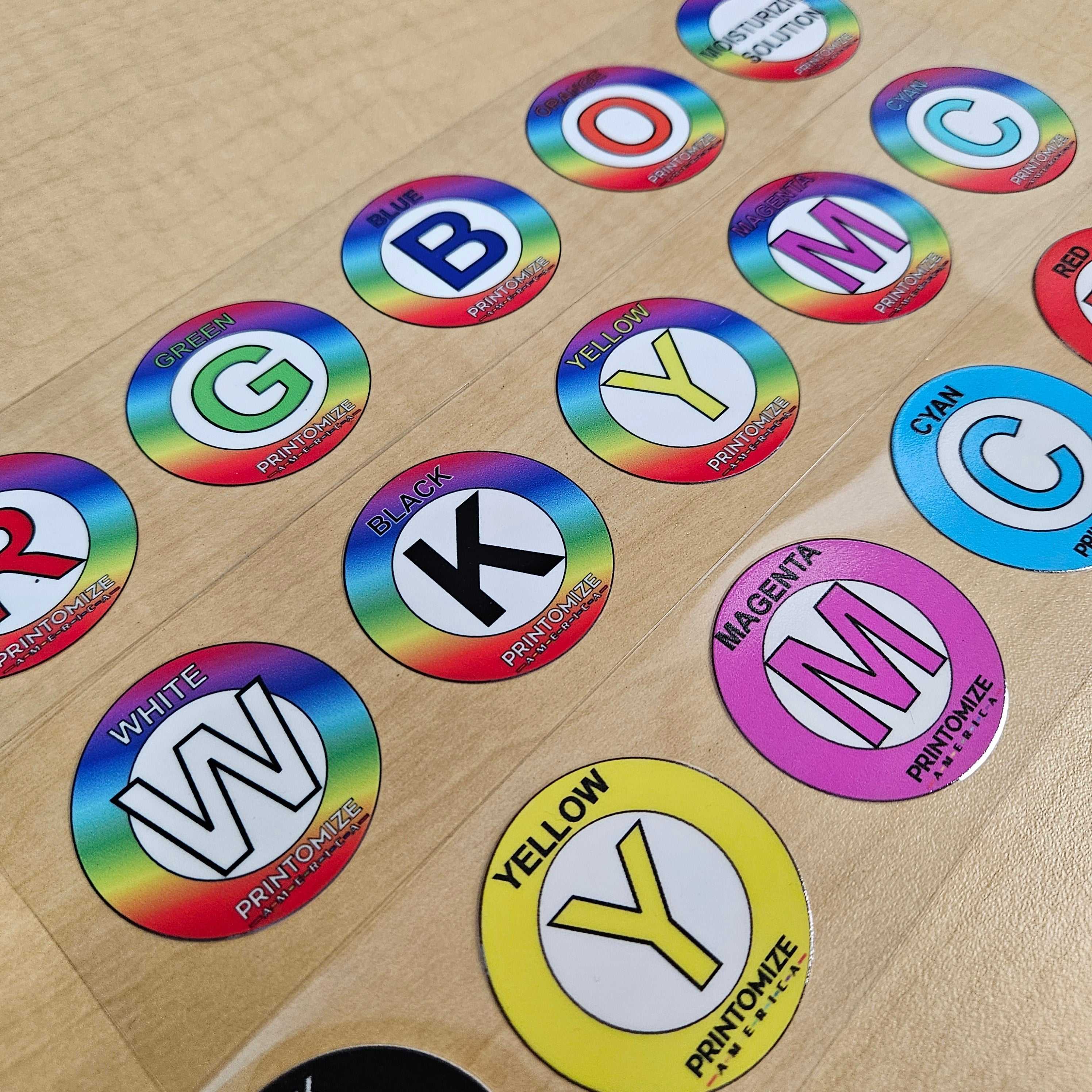UV DTF Transfers color swatch stickers by Printomize America, featuring various colors including red, blue, yellow, and black, arranged on a wooden surface.